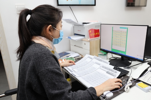 临源居民区党总支书记、居委会主任徐茜在为辖区不同年级孩子打印课程表。